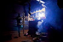 Clouded leopard (Neofelis nebulosa) skin hanging inside a kitchen belonging to a Naga headman, with a woman cooking nearby, Shatuza, Nagaland, India, 2011.