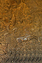 Bas-reliefs with soldiers in horse-drawn carriages, decorating the ground level of the temple at Angkor Wat, Angkor, Cambodia. March 2013