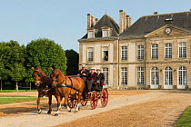 Two traditionally dressed couples driving two Franches-Montagnes horses, harnessed to a phaeton, in the Cour D'Honneur of the Haras Du Pin, France's oldest national stud, at Le Pin-au-Haras, Orne, Low...