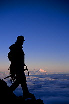 Climber on Mount Rainier with Mount Adams in the distance, Mount Rainier National Park, Washington, USA. Model Released.