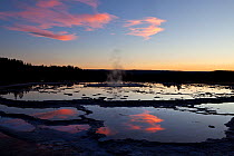 Clouds reflected in Great Fountain Geyser at dusk, Yellowstone National Park, Wyoming, USA. July 2013.