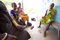 Tanzanian women sat with mobile phones waiting to charge them at a solar-powered charging booth, Miono Region, Tanzania.