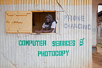 Man awaiting business in a mobile phone charging booth, Yala, Kenya.