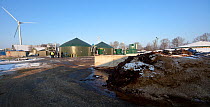 A pile of digestate, a waste product in the biogas production process, used as an organic soil improver, with a Biogas plant in the background, Spain, January 2013.