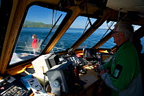 Man at controls of whale watching boat, Johnstone Strait, East Coast, Vancouver Island, Telegraph Cove, British Columbia.
