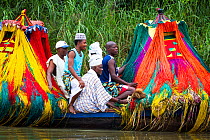 'Zangbeto' traditional guardians of the night, and priests in boat going to visit another village for a voodoo / vodun ceremony, Benin, Africa, February 2011.