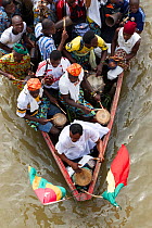 Villagers travelling in dugout canoe frome on village to another for traditional voodoo / vodun ceremony, Benin, February 2011.