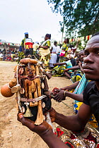 Man holding several 'fetishes' attached to a glass bottle, at a voodoo / vodun ceremony, Benin, Africa. February 2011.