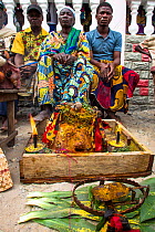Men sitting with a 'fetish' during Voodoo ceremony, Benin, Africa. February 2011.
