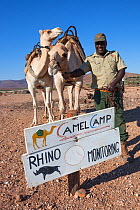 Save the Rhino Trust camel camp patrol team member Hans Ganaseb with camels, Kunene region, Namibia, May 2013