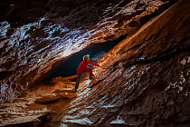 Man exploring Forat de l'Or cave, Terradets Canyon, Pyrenees, Lleida, Catalonia, Spain, December 2012.