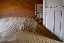 Sand filling room in Kolmanskop Ghost Town, an old diamond-mining town where shifting sand dunes have encroached abandoned houses, Namib Desert Namibia, October 2013.