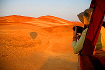 Tourists taking photos from hot air balloon ride over the Namib desert, Namibia, February 2005.