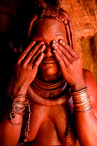 Himba woman applying Otjize (a mixture of butter, ochre and ash) to her skin, Kaokoland, Namibia, September 2013.