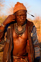 Himba man talking on a mobile phone. Himba village, Kaokoland, Namibia, September 2013.