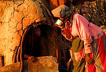 Herero woman drinking next to hut, Kaokoland, Namibia, February 2005.
