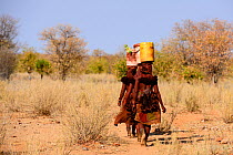 Himba women carrying goods on their heads. Kaokoland, Namibia, September 2013.