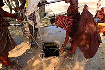Himba woman with a rope pulling water from a well. Kaokoland, Namibia, September 2013.