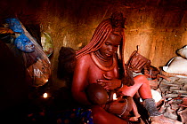 Himba woman breastfeeding her baby inside her hut, Kaokoland, Namibia, September 2013.