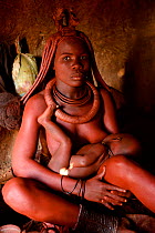 Himba woman breastfeeding her baby inside her hut. Kaokoland, Namibia, September 2013.