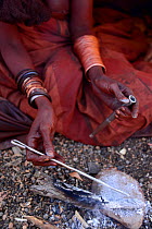 Himba woman preparing nasal snuff tobacco. Himba village, Kaokoland, Namibia, September 2013.
