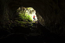 Tourist exploring the lava caves on the island of Santa Cruz, Galapagos Islands, January 2012. Model released.