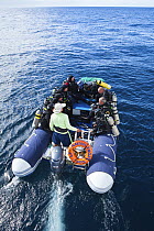 Scuba divers travelling to dive site aboard inflatable boat from the Galapagos Aggressor live-aboard dive boat, Galapagos Islands. September 2011. Property and model released.
