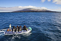 Scuba divers travelling to dive site aboard inflatable boat, Galapagos Islands, September 2011. Property and model released.