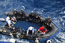 Scuba divers travelling to dive site aboard inflatable boat, Galapagos Islands, September 2011. Property and model released.