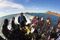 Scuba divers in inflatable going to dive site. Galapagos Islands, model released.