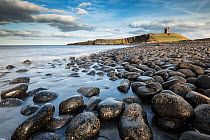Round rocks on beach with Dunstanburgh Castlle in the distance, Northumberland, UK, April 2013.