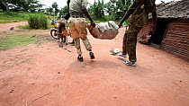 THIS VIDEO CLIP WILL BE AVAILABLE TO VIEW ONLINE SOON. TO VIEW NOW, PLEASE CONTACT US. -Ecoguards putting  a sack of bushmeat onto a motorbike after an inspection, Bayanga village, Dzanga-Ndoki Nation...