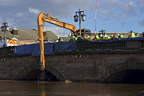 Crane removing the debris raft trapped by Worcester Bridge due to record floods, Worcestershire, England, UK. 16th February 2014.