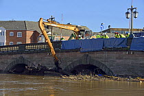 Crane removing the debris raft trapped by Worcester Bridge due to record floods, Worcestershire, England, UK. 16th February 2014.