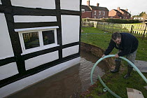 Resident trying to pump out water from cottage during February 2014 flood, Upon upon Severn, Worcestershire, England, UK, 8th February 2014.