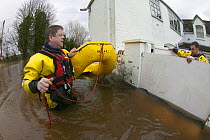 Rescue workers entering property from safety of  lightweight boat to check property for its safety and rescue homeowners in February 2014 flood of properties by River Severn.