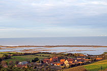 View over flooded grazing marsh and breached shingle coastal defense after the 6th December east coast tidal surge, with the village of Salthouse in the foreground, Norfolk, England, UK, December 2013...