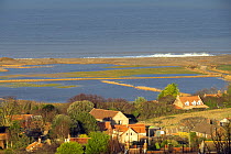 View over flooded grazing marsh and breached shingle coastal defense after the 6 December east coast tidal surge, with the village of Salthouse in the foreground, Norfolk, England, UK, December 2013.