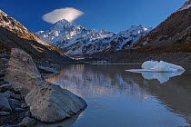 Mount Cook / Aoraki (height 3754m) with cap cloud forming, above the Hooker Valley, glacier lake in foreground. Aoraki/Mount Cook National Park, MacKenzie District, Canterbury Region, New Zealand. Dec...