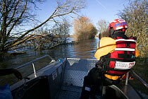 Rescue worker steering water borne craft which ferries villagers from Langport to Muchelney during January 2014 flooding, in Somerset Levels, England, UK, 11th January 2014.