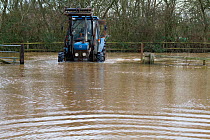 Tractor entering flooded farm drive during January 2014 flooding, Somerset Levels, England, UK, 10th January 2014.