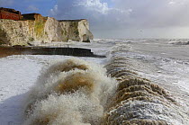 Waves crashing beach with chalk cliffs during a winter storm at Birling Gap, Sussex, England, UK, 15th February 2014.