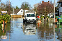 Van carrying sand bags to residents of flooded street, with Labrador retriever, Weybridge, Surrey, England, UK, 10th February 2014.