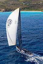 Mega yacht with white spinnaker sailing around island in the 2013 St. Barths Bucket Regatta, March 2013, Caribbean. All non-editorial uses must be cleared individually.