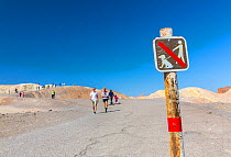 No dog walking sign and tourists at Zabriskie Point, Death Valley National Park, California, USA, March 2013.