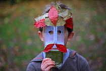 Boy with face made out of milk bottle and leaves, Norwich, UK, November 2013. Model released.