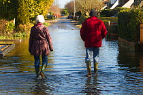 Residents walking through February 2014 floods from River Thames, Wraysbury, Surrey, England, UK, 16th February 2014.