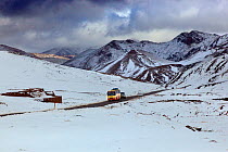 Bus and car on road crossing the Atlas Mountains  in late snow, Morocco, North Africa, March 2011.
