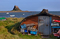 Fisherman's shed made from old upturned boat with Lindisfarne Castle behind, Lindisfarne Island, Northumberland , UK, Octobber 2013.