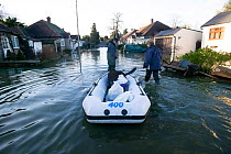 Residents transporting their dog on a rib during February 2014 floods, Sunbury on Thames, Surrey, England, UK, 15th February 2014.
